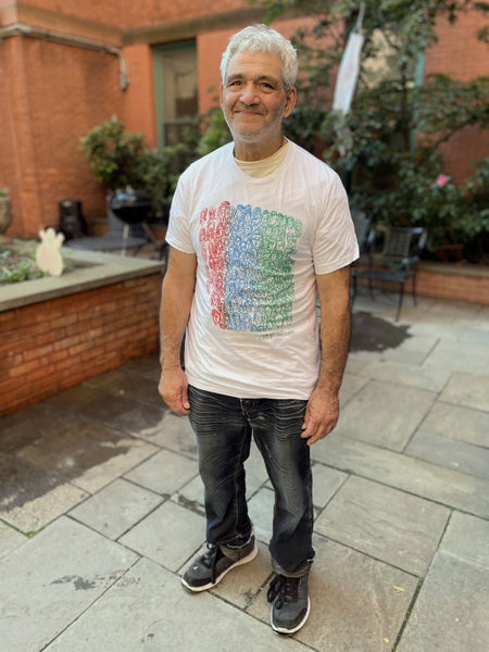 Artist wearing his t-shirt design stands in brick couryard, looking at the camera. 